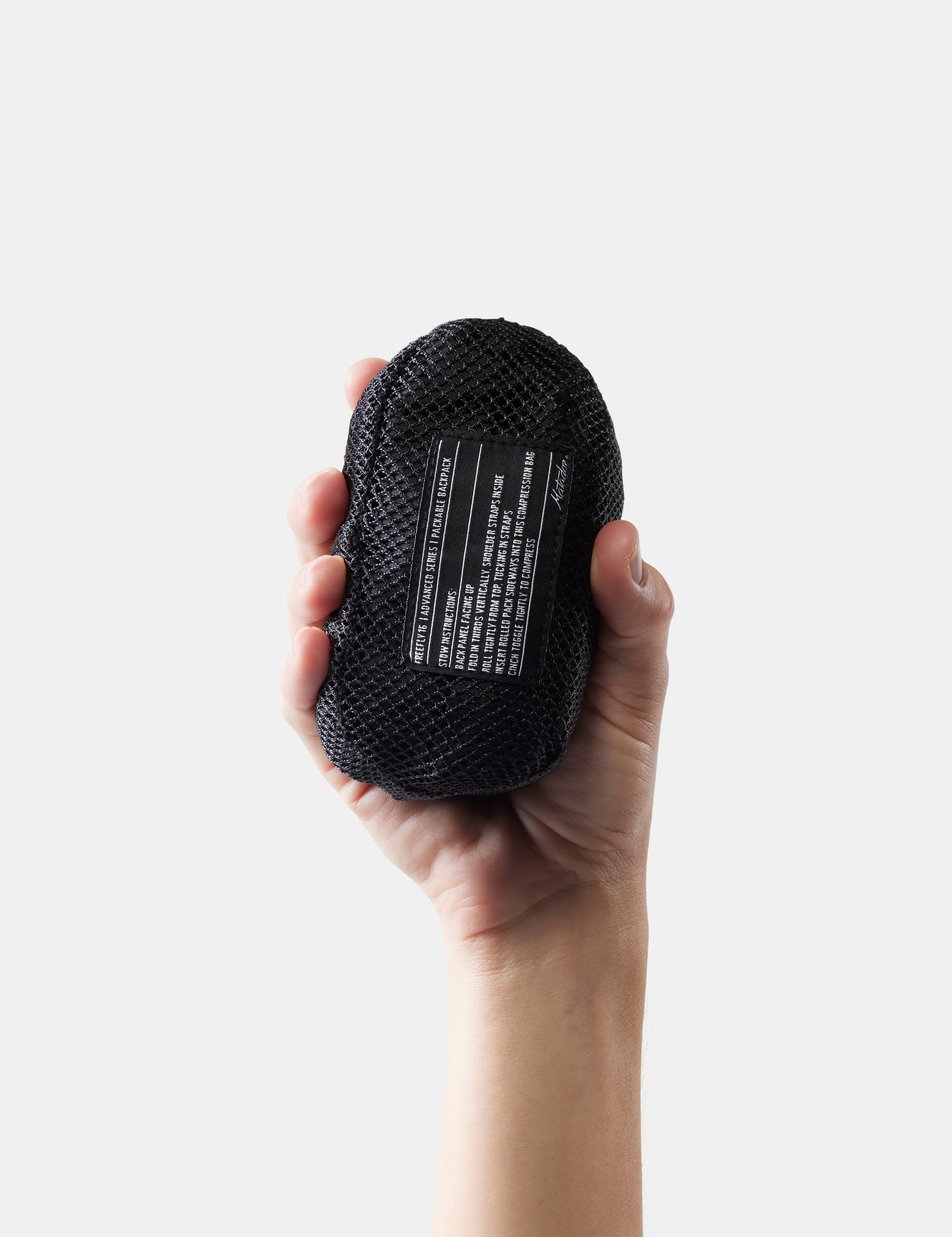 Hand holding a black packed up with text on a white background