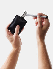 Person using a black Sharpie marker holder to sharpen a white Sharpie pen on a light gray background