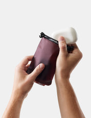 hands placing soap into garnet soap bar case on white background