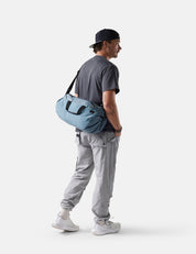 Man carrying a blue duffel bag on a white background