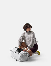 Person digging in white backpack against a white background